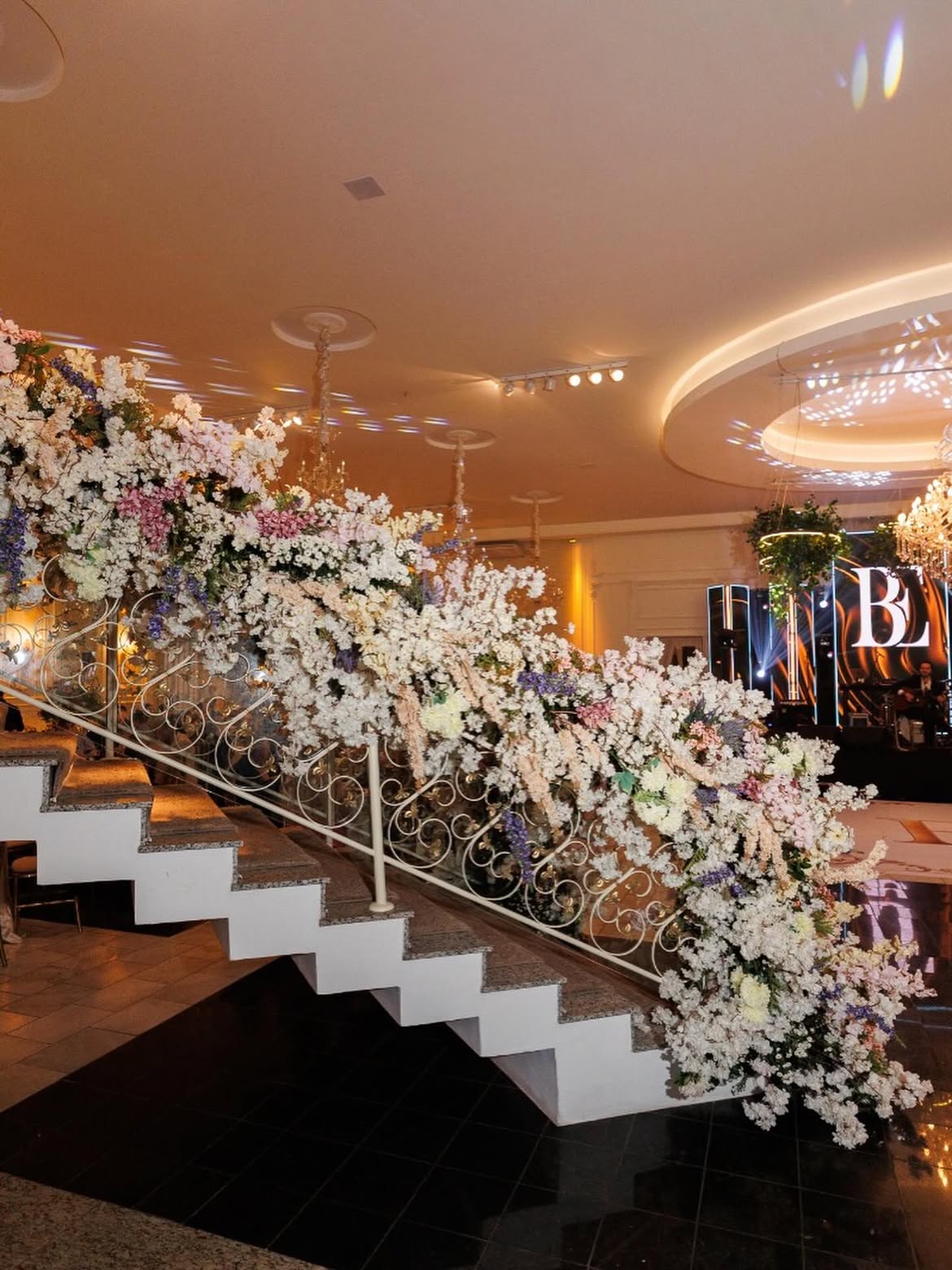 Corrimão de escada coberto por flores claras em festa de debutante